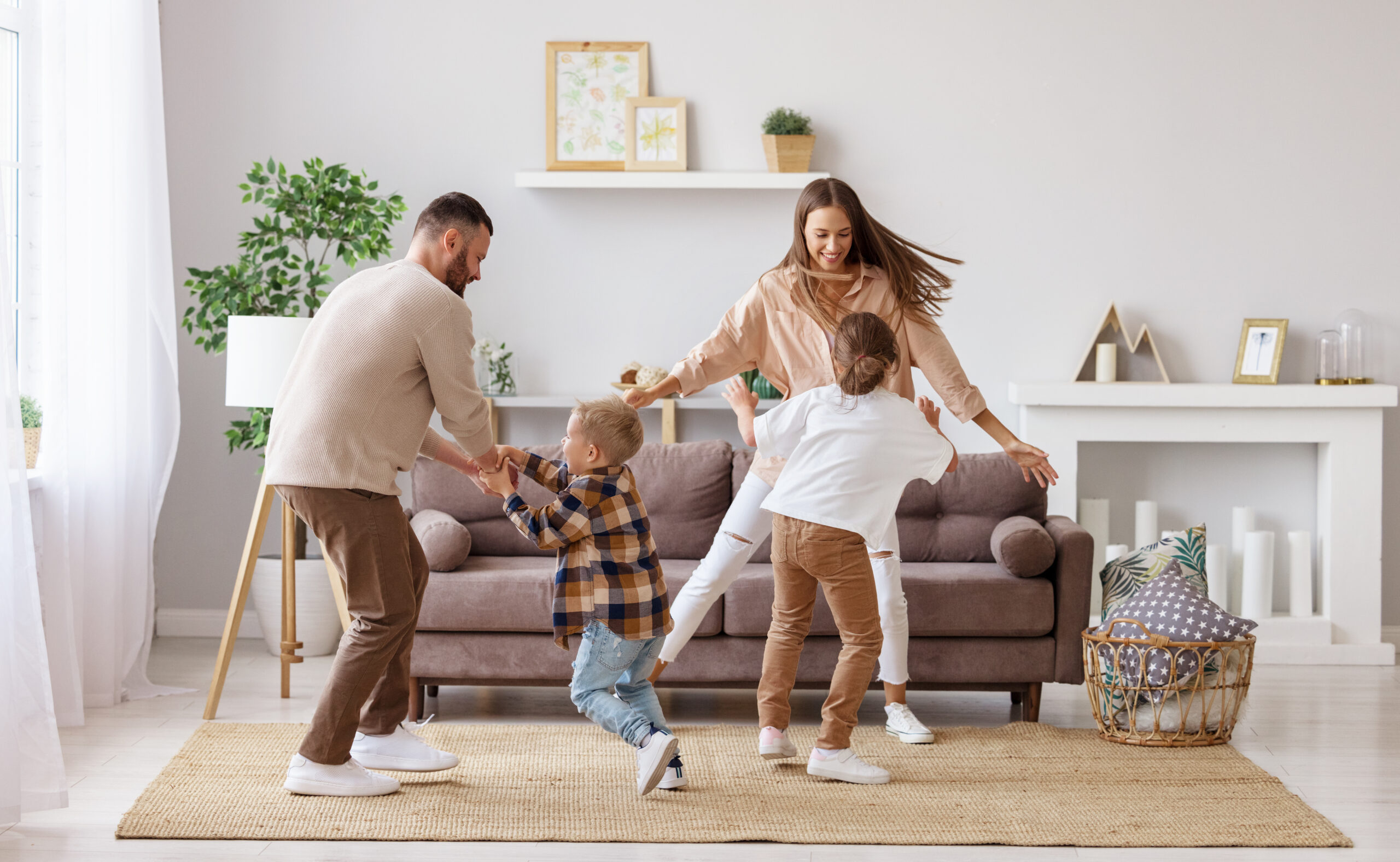 Happy family mother father and kids daughter and son dancing and having fun at home