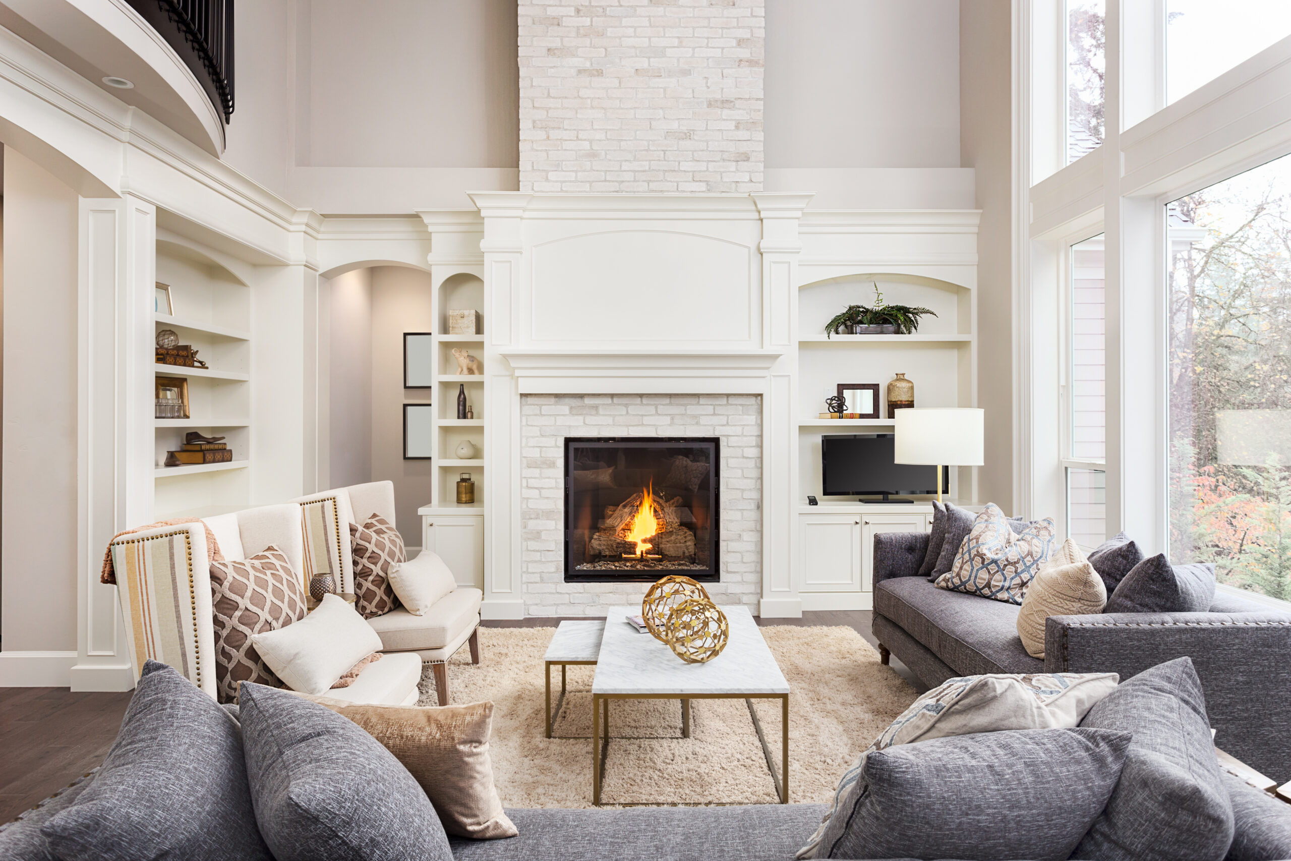 Elegant living room with fireplace, white brick, built-in shelves, and neutral-toned sofas. Home interior design.