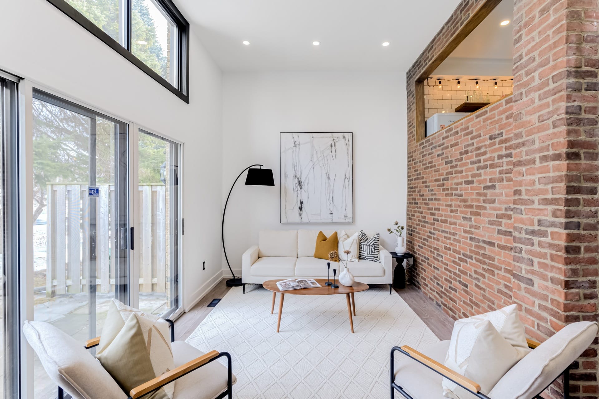 Staged living room: white sofa, modern art, brick wall accent. Interior design for home staging.