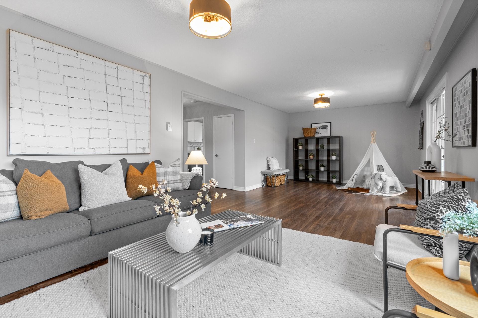 Staged living room showcasing modern decor, gray couch, and kids' teepee for real estate appeal.