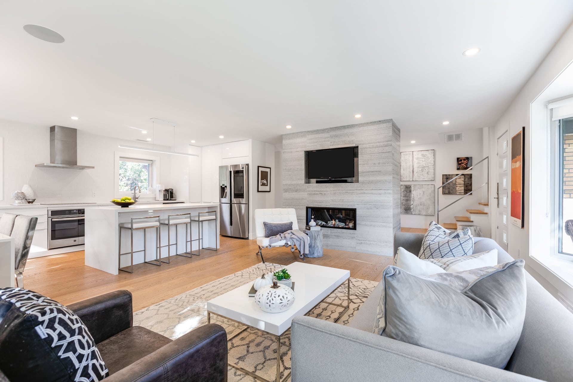 Staged home interior: Open concept living area with modern kitchen, fireplace, and stylish furniture. Real estate staging.