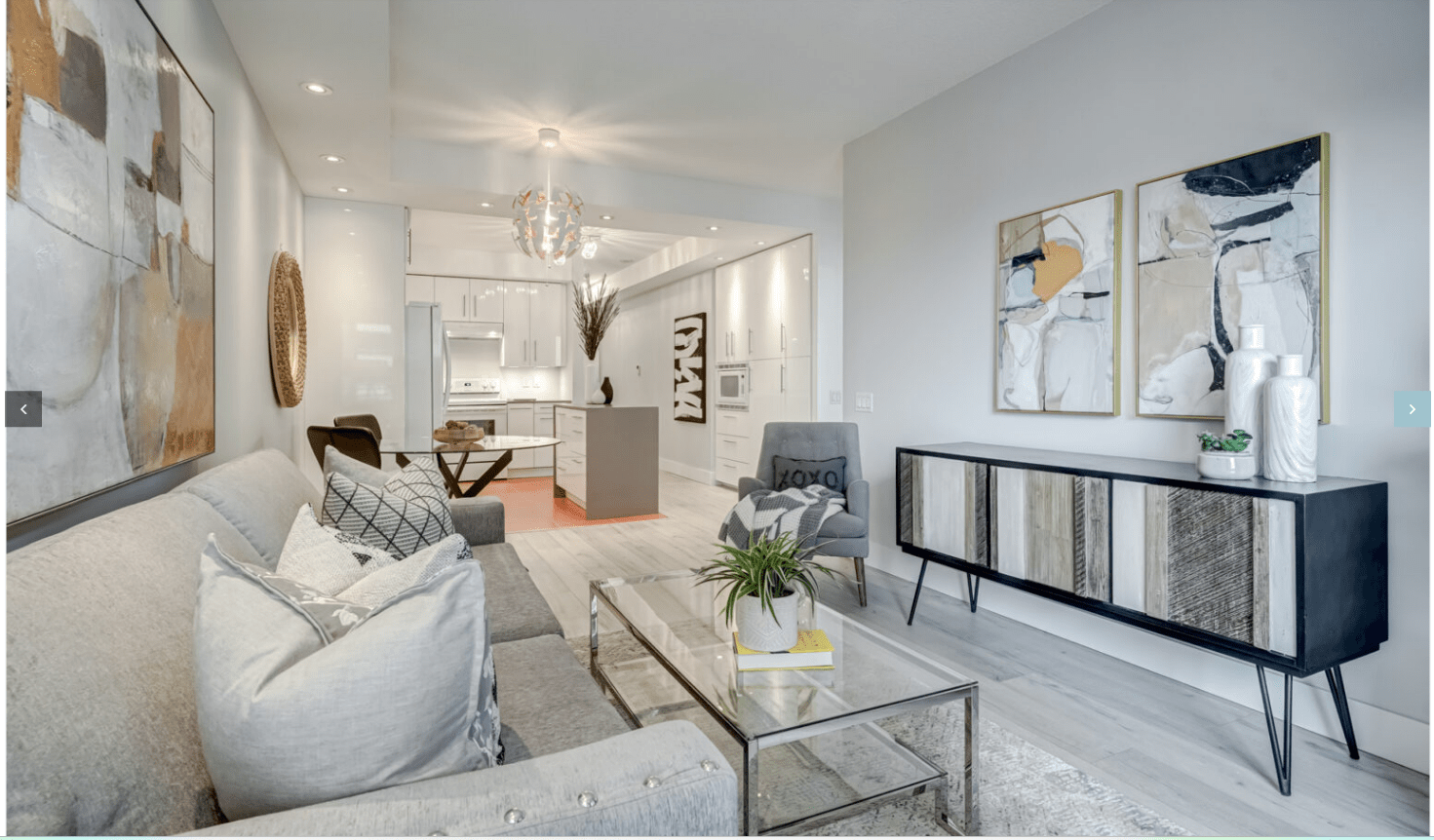 Staged condo interior: Living room with sofa, glass coffee table, modern art, kitchen island. Real estate staging for sale.