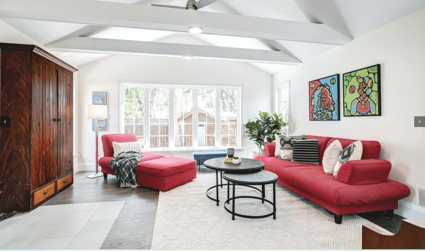 Staged living room showcasing red sofa, ottoman, and modern art. Bright, airy interior design for real estate staging.