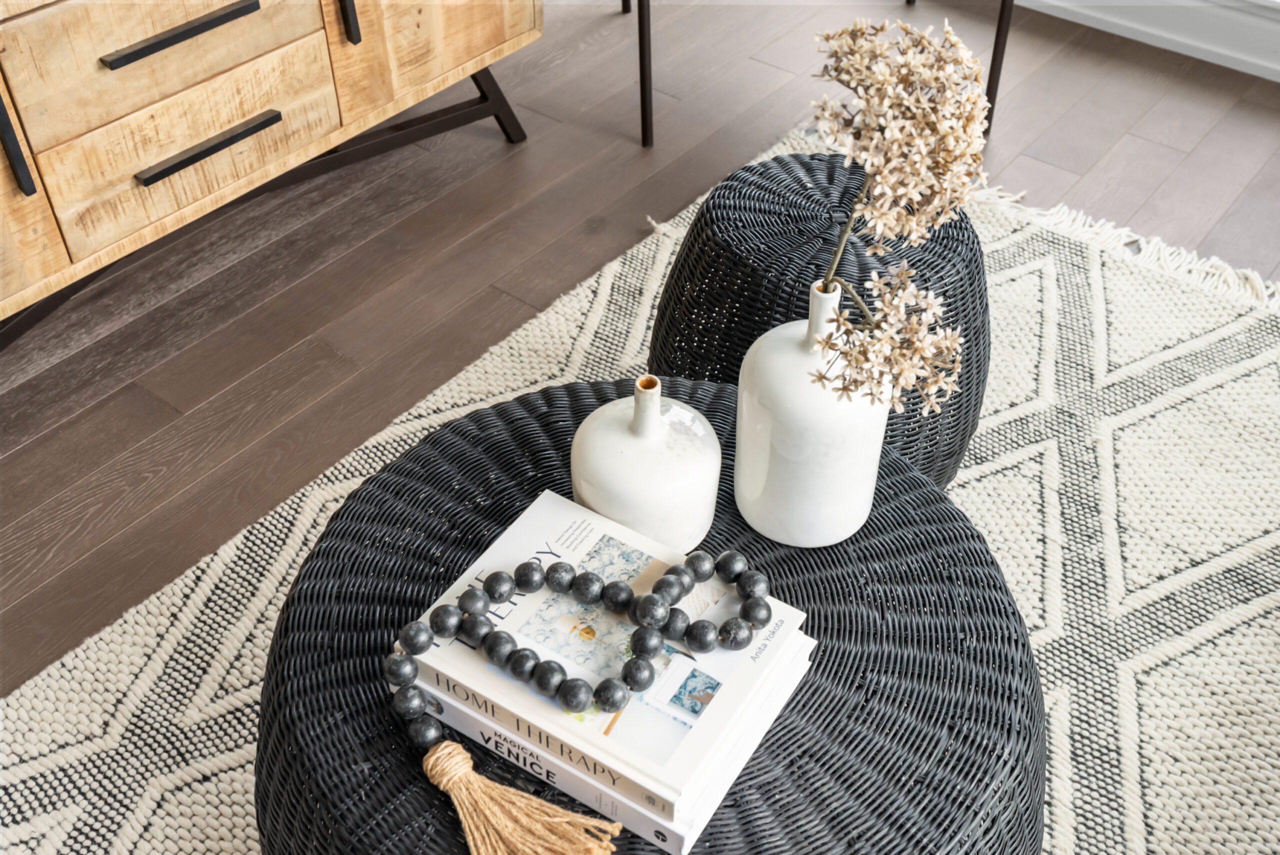 Design consultation: Interior design featuring a black wicker table, books, vases, and decorative beads on a patterned rug.